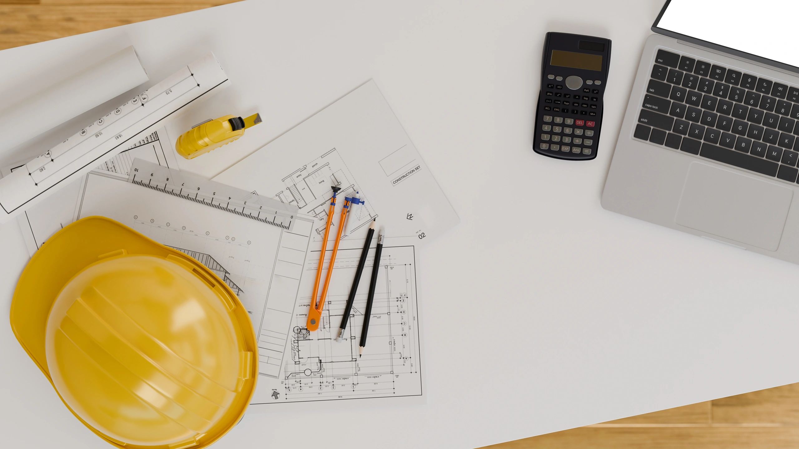 Construction planning desk with blueprints, laptop, and engineering tools